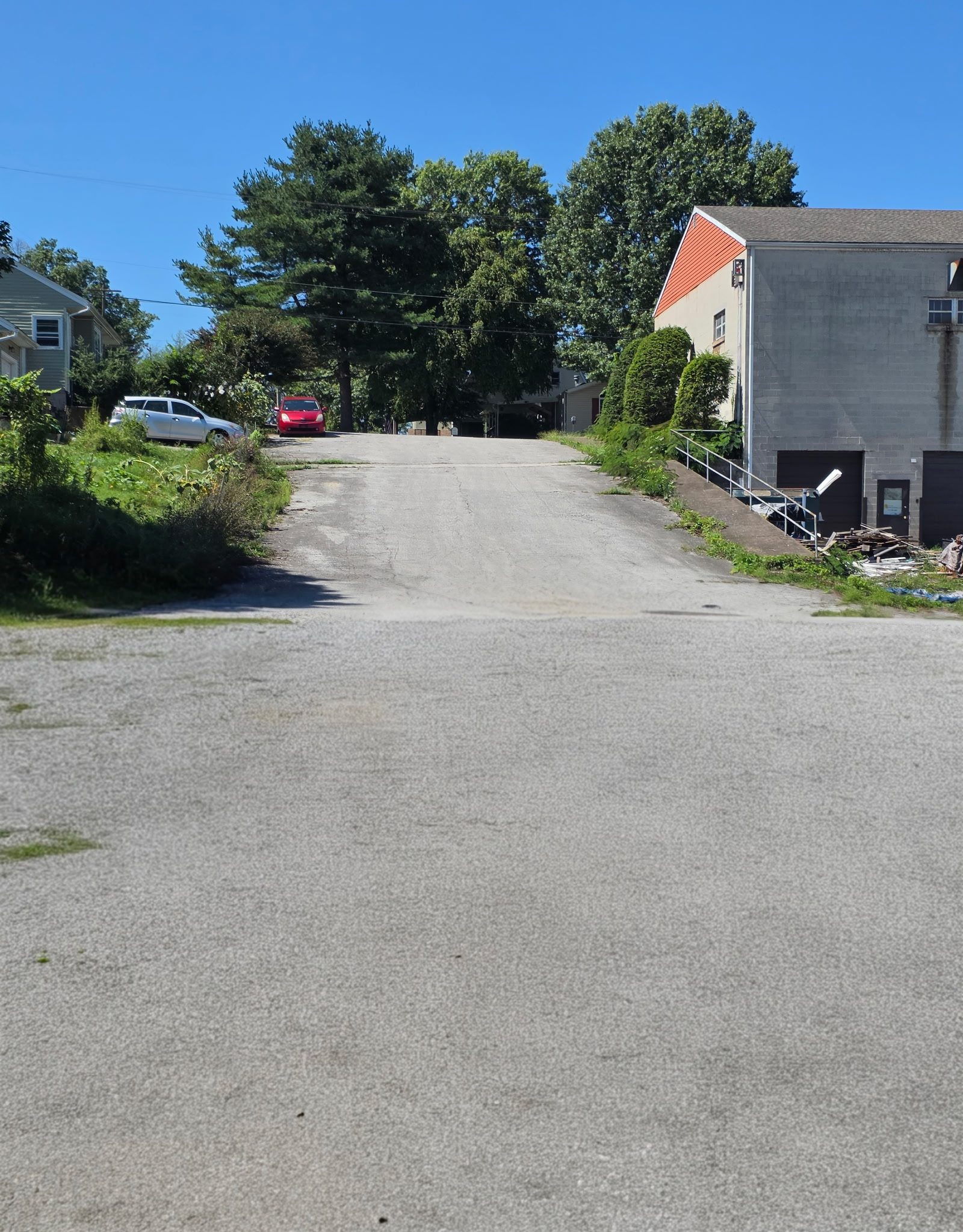 The paved drive rising from the road into Safe Haven Storage, with the block storage building on the right and tall trees at the top of the hill