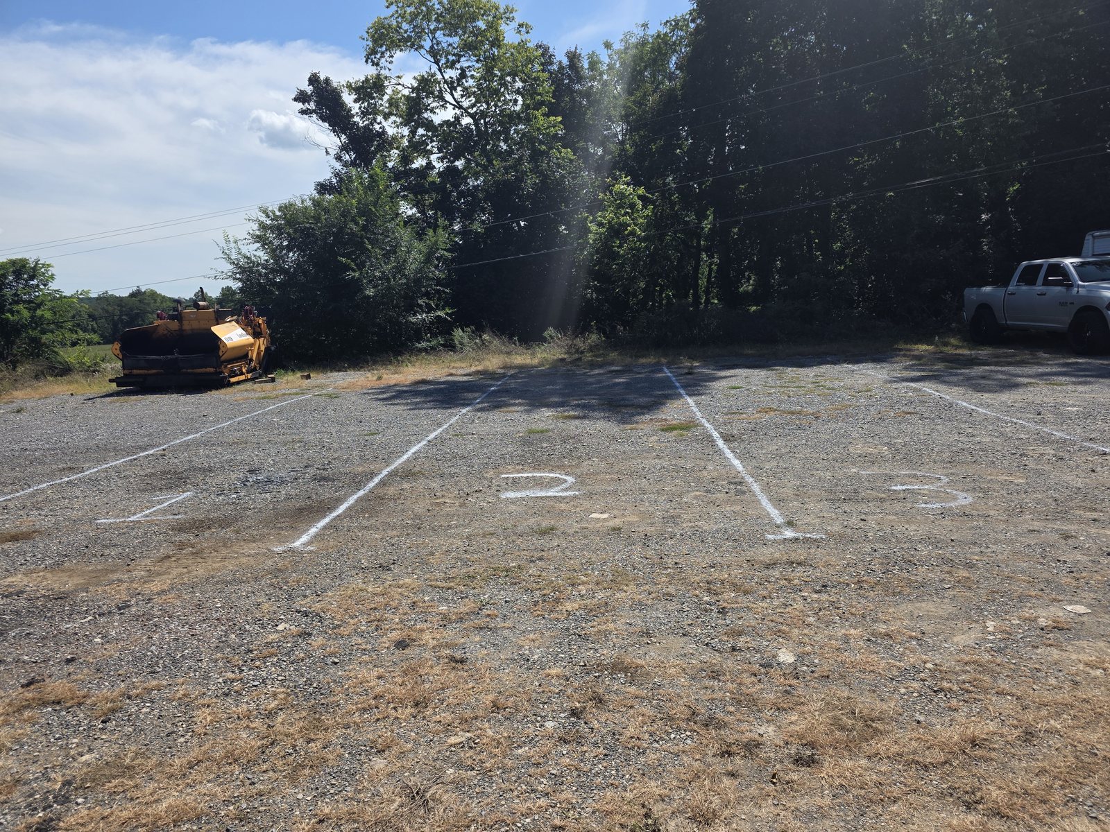 Numbered outdoor parking spaces marked out in white on the gravel lot at Safe Haven Storage, with trees along the far edge