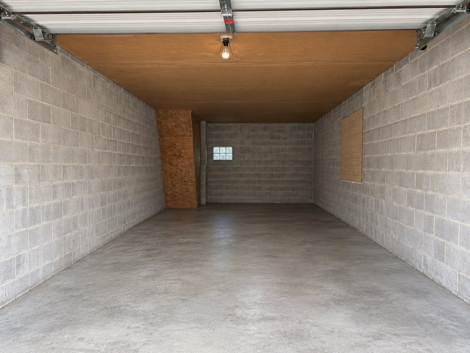 Inside a drive-up unit at Safe Haven Storage: bare block walls, a sealed concrete floor, a glass block window at the back and the roll-up door open at the front